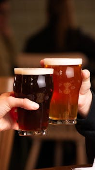Two people toasting with pints of beer in a cozy pub setting, showcasing camaraderie and celebration.